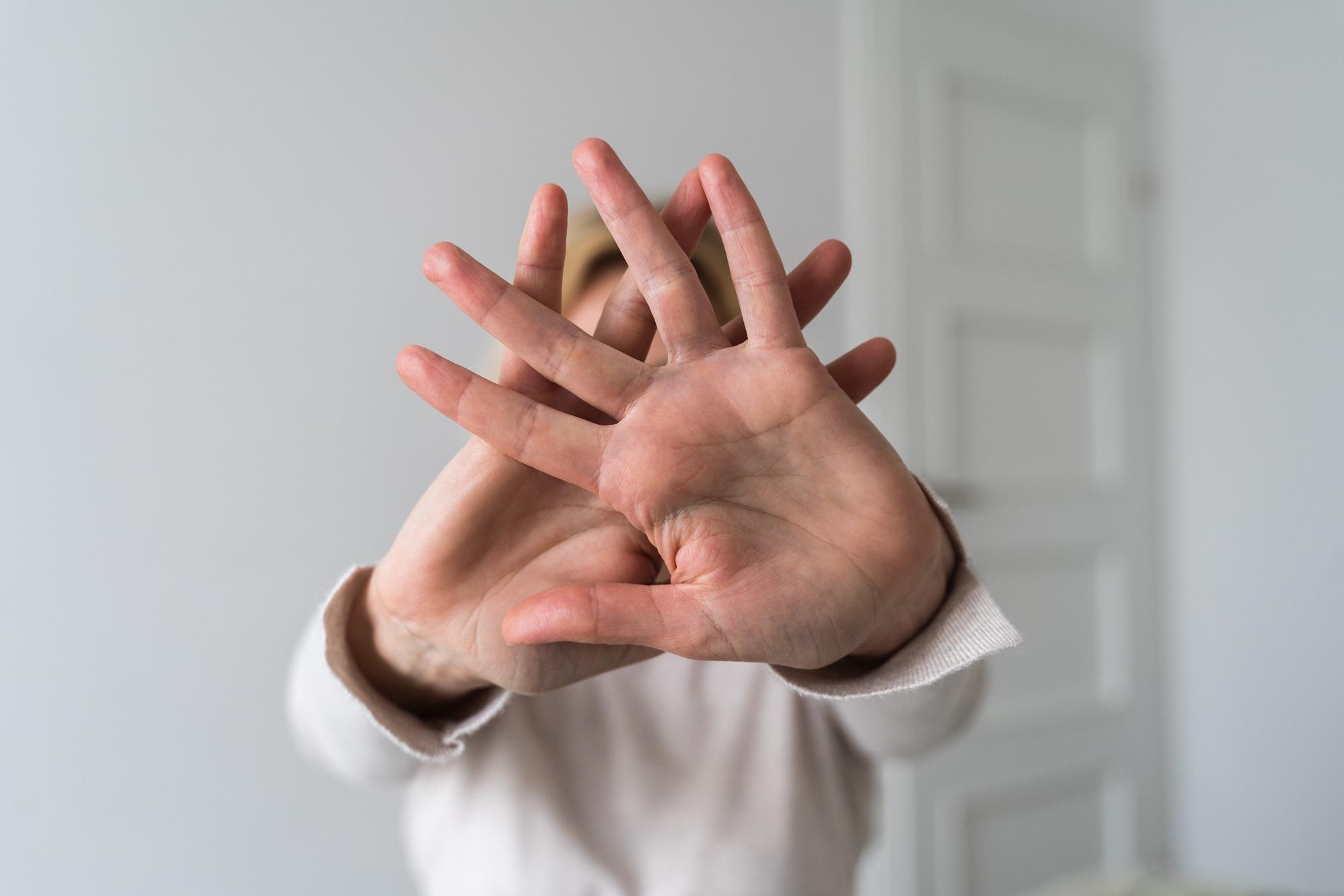 Woman showing stop gesture with hand at home. Abuse, mental health, toxic relationship problem.