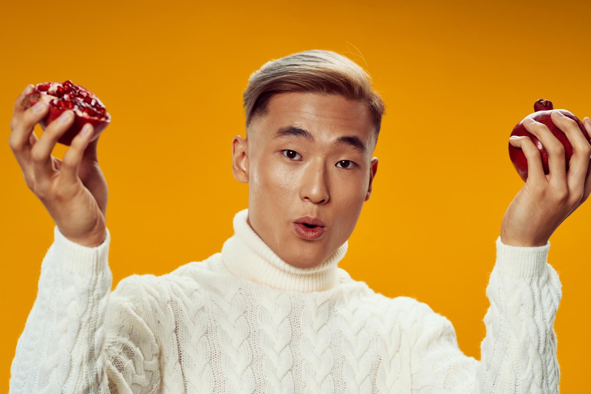 a man of Asian appearance in a white sweater with grenades in his hands