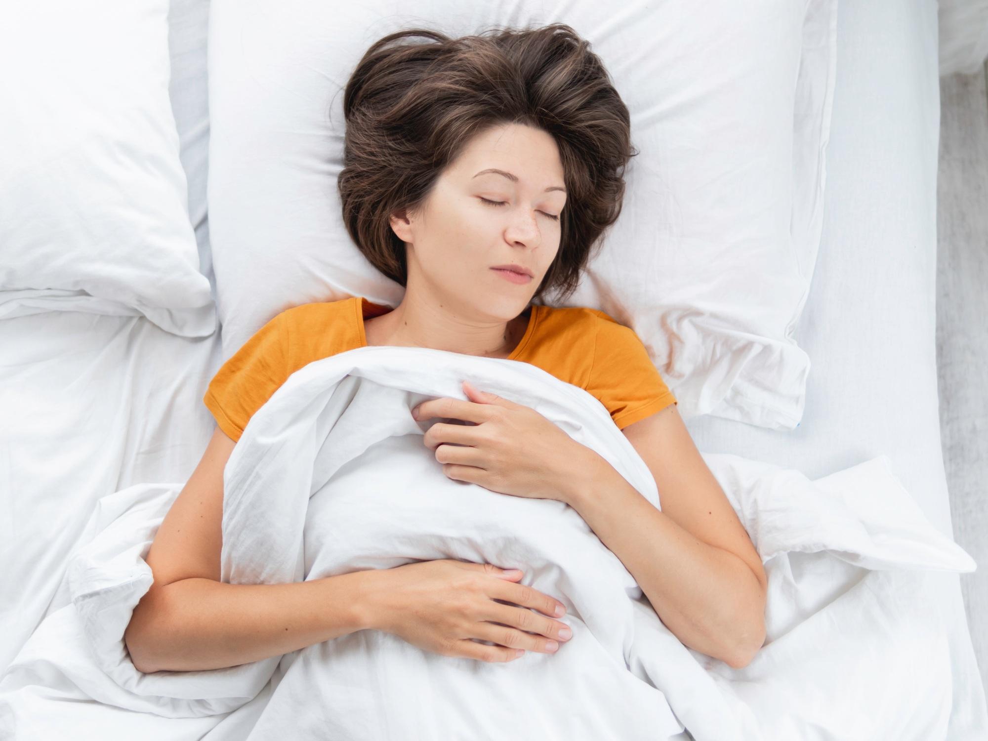 Top view on Caucasian woman sleeping in bed. Healthy sleep on white bed linen.