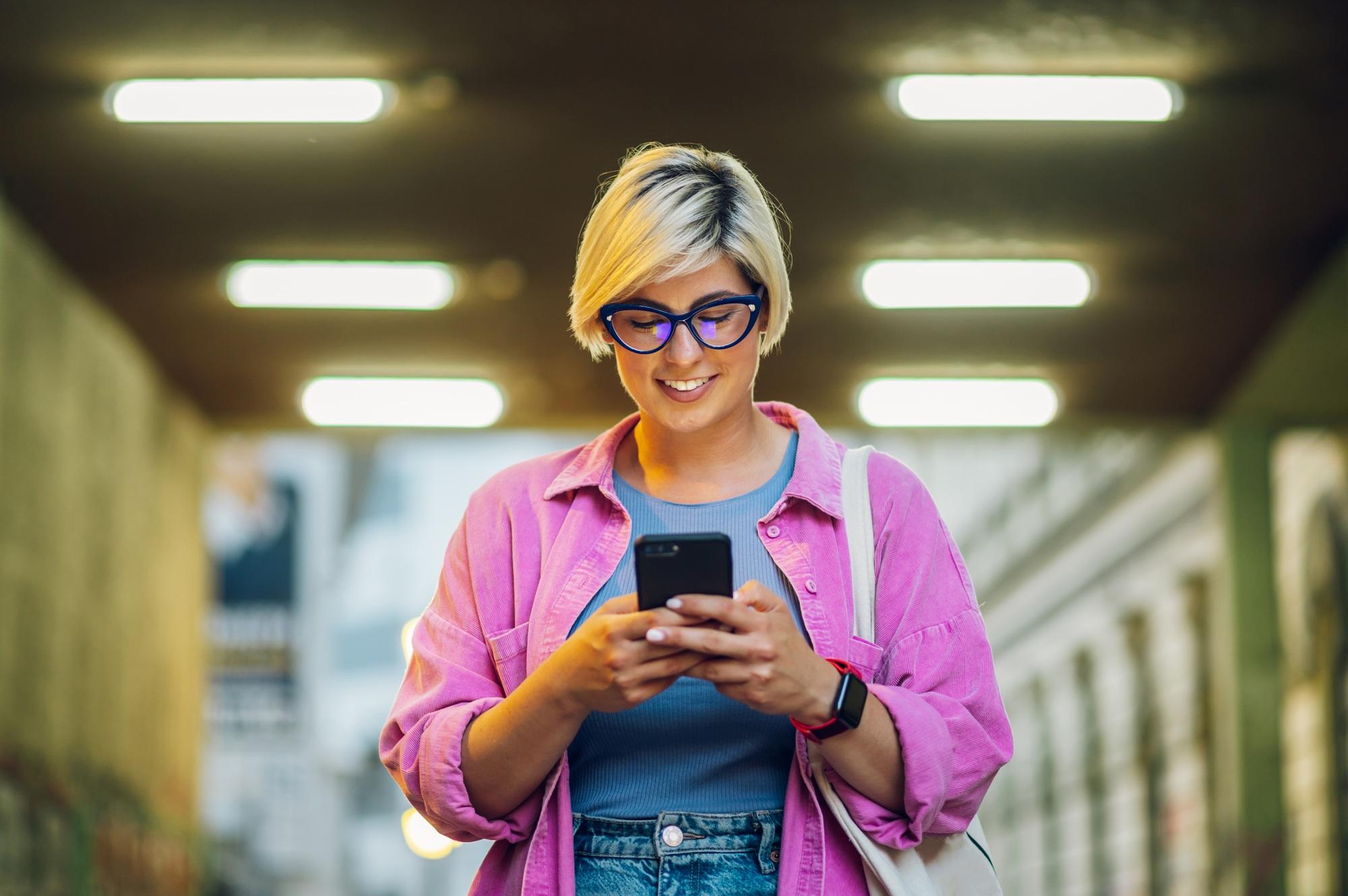 Young plus size woman using smartphone while walking in the city.