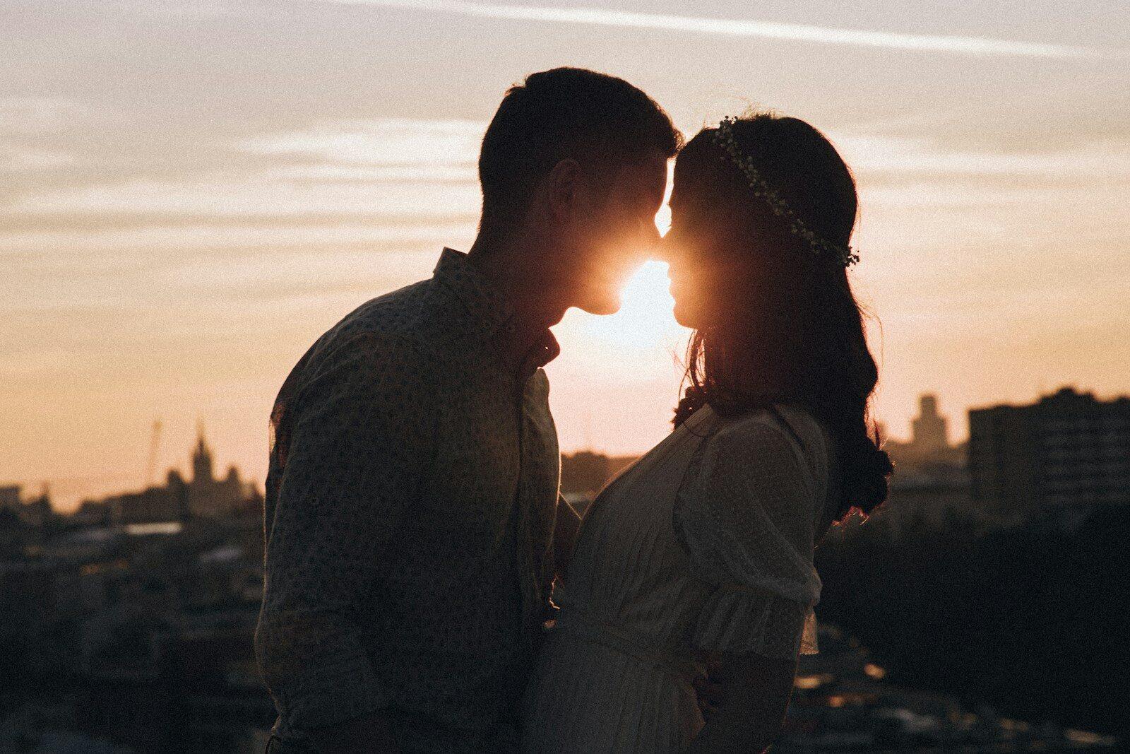 a man and a woman standing in front of a sunset